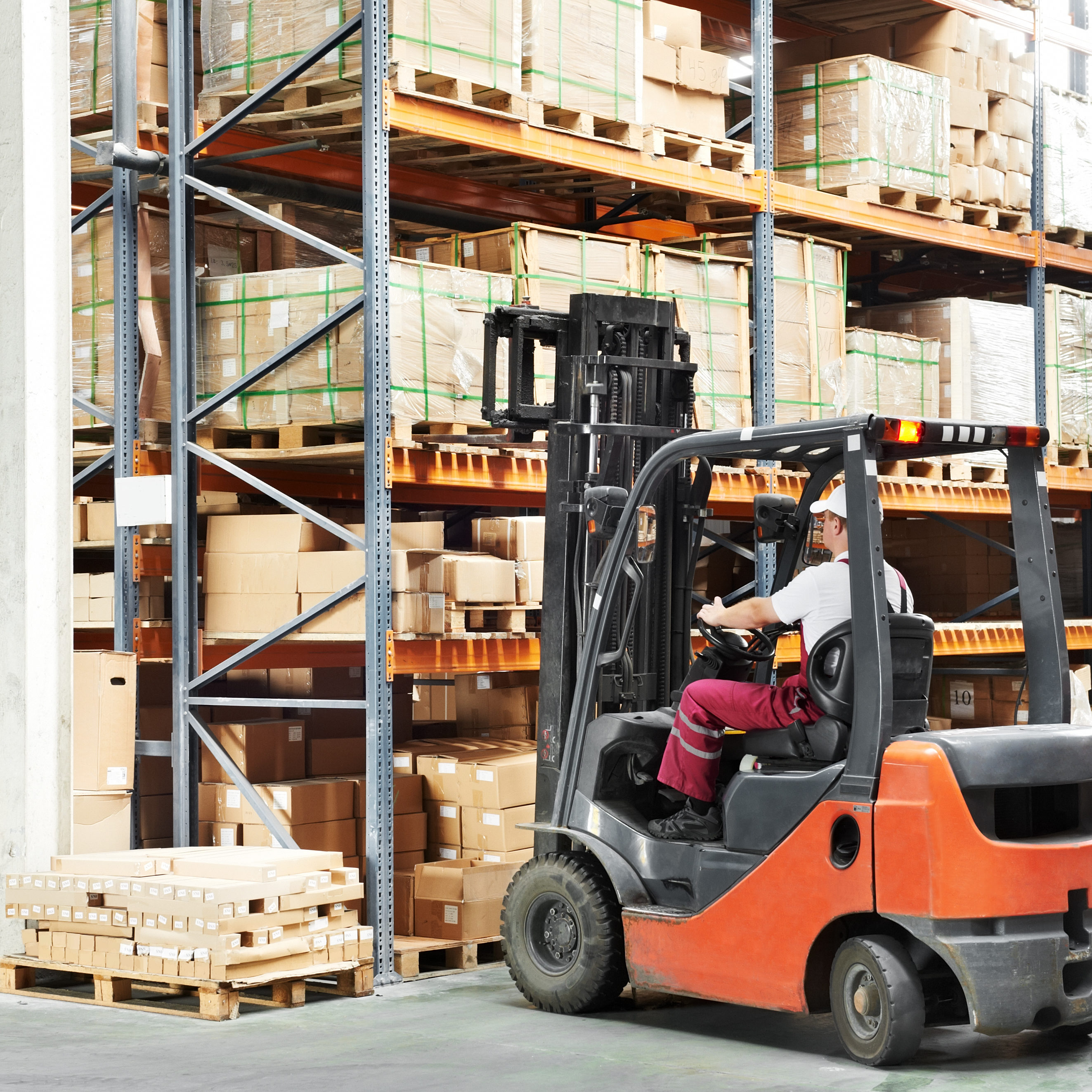 worker driver at warehouse forklift loader works warehouse worker driver in uniform loading cardboxes by forklift stacker loader