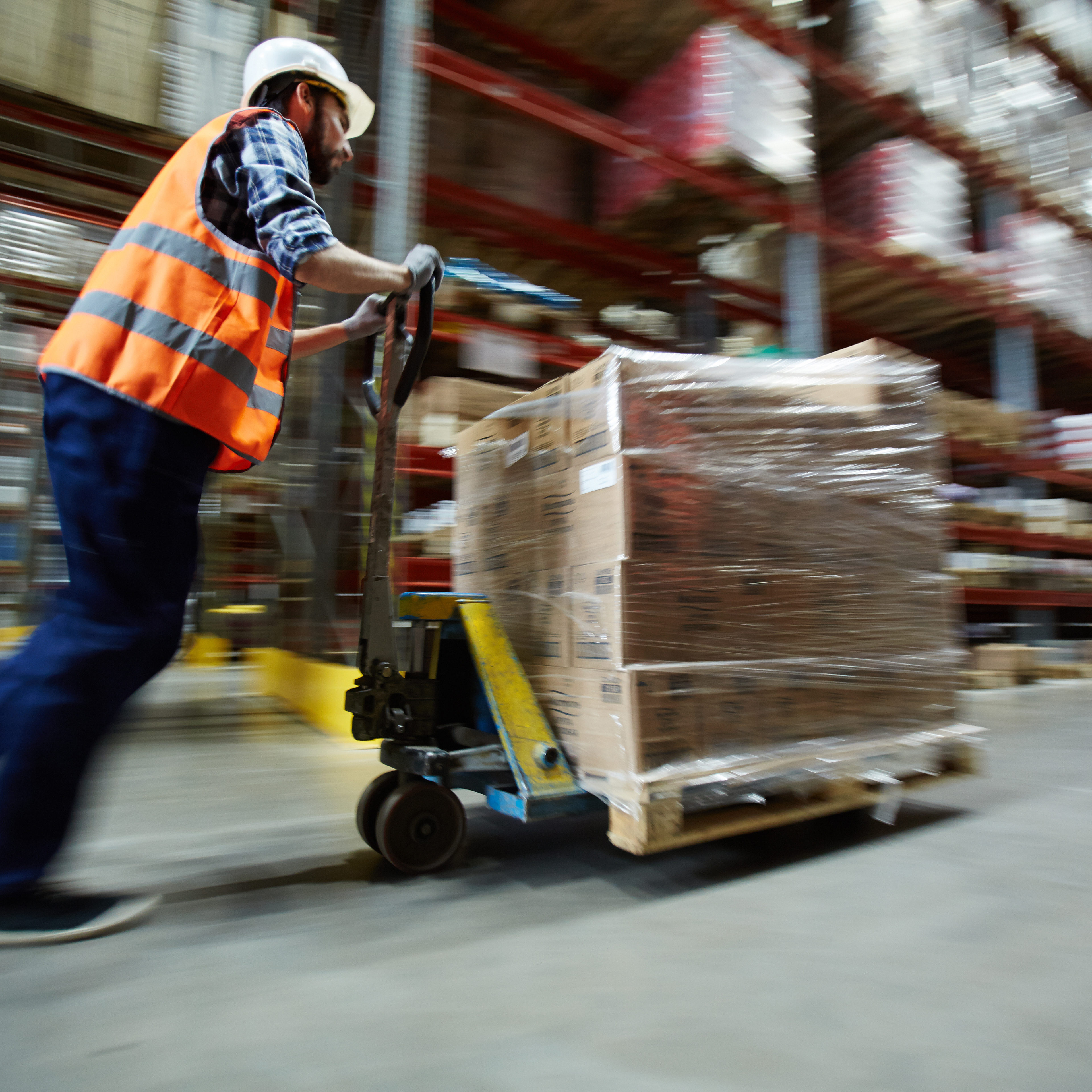 Working in distribution center Warehouse worker pushing forklift at work